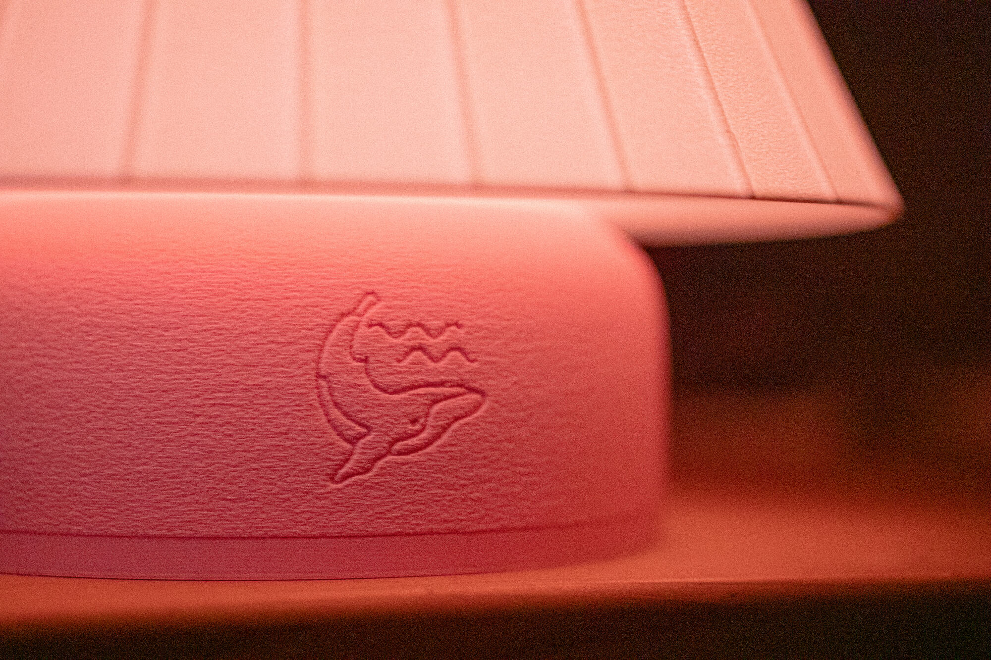 Détail d'une lampe rose avec une baleine embossée